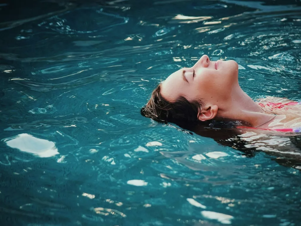 Woman relaxing in the pool with red swimsuit