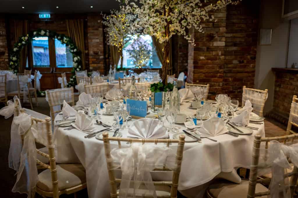 Moat Suite set up for a wedding with tall flower centrepieces and white chair sashes