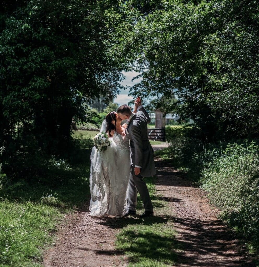 Wedding couple kissing outside in the sunshine